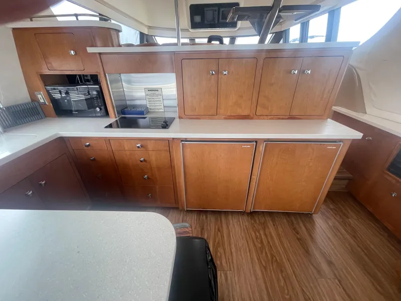 Slide: The Image of Interior of a 1999 Carver Voyager yacht kitchen with wooden cabinets and modern appliances. - 13