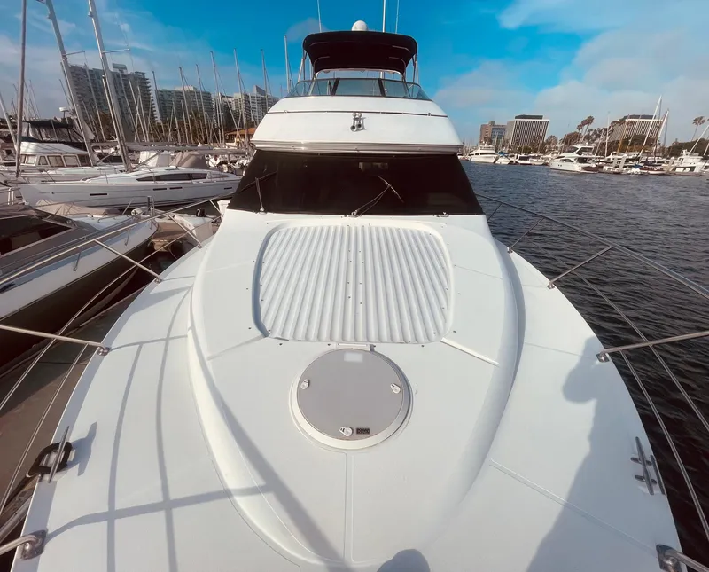 Slide: The Image of 1999 Carver Voyager yacht docked in marina, surrounded by sailboats under a clear blue sky. - 2