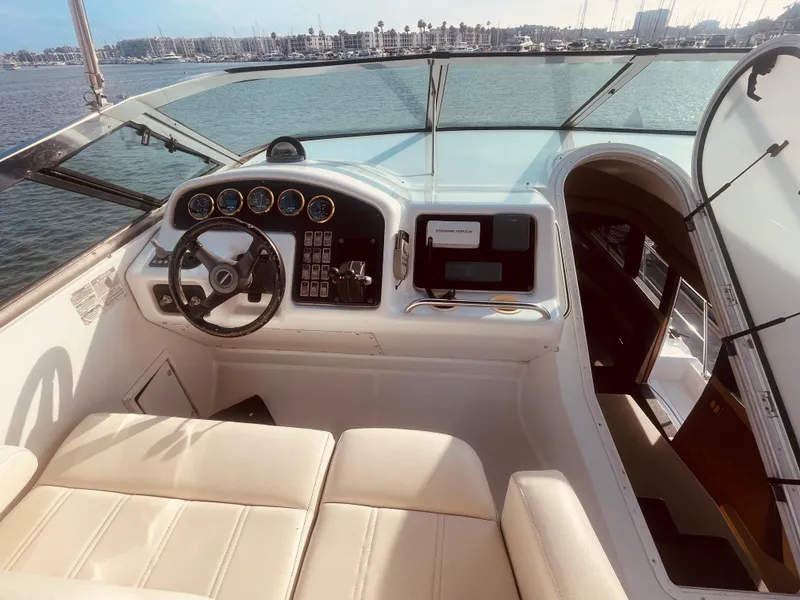 Slide: The Image of 1999 Carver Voyager boat cockpit with steering wheel and control panel, docked by the water. - 6
