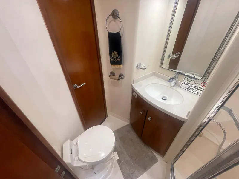 Slide: The Image of 1999 Carver Voyager bathroom with toilet, sink, mirror, and wooden cabinetry. - 28