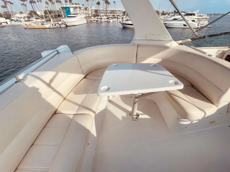 Slide: The Image of 1999 Carver Voyager yacht with white seating and table, docked in a marina. - 9