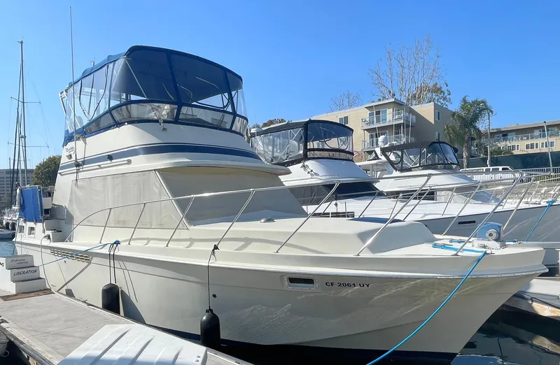 The Image of 1984 Uniflite Double Cabin Motor Yacht docked at marina under clear blue sky. - 0