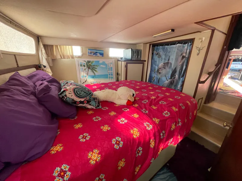 Slide: The Image of 1984 Uniflite Double Cabin Motor Yacht bedroom with vibrant red floral bedding and cozy decor. - 13