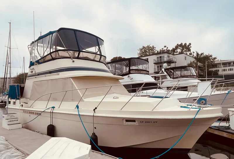 Slide: The Image of 1984 Uniflite Double Cabin Motor Yacht docked at marina, featuring spacious deck and cabin. - 14