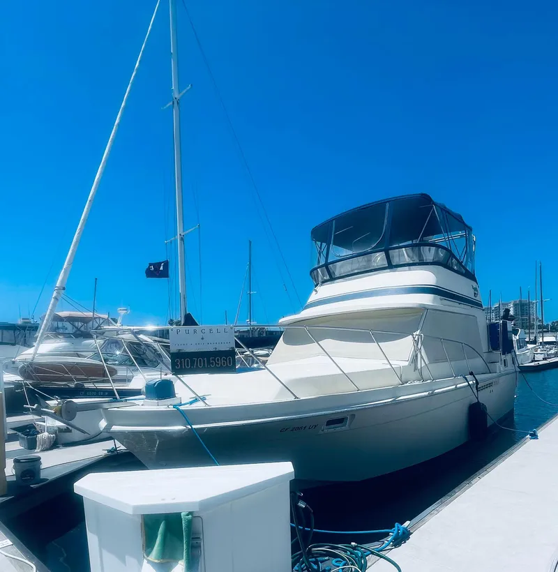 Slide: The Image of 1984 Uniflite Double Cabin Motor Yacht docked at marina under clear blue sky. - 15