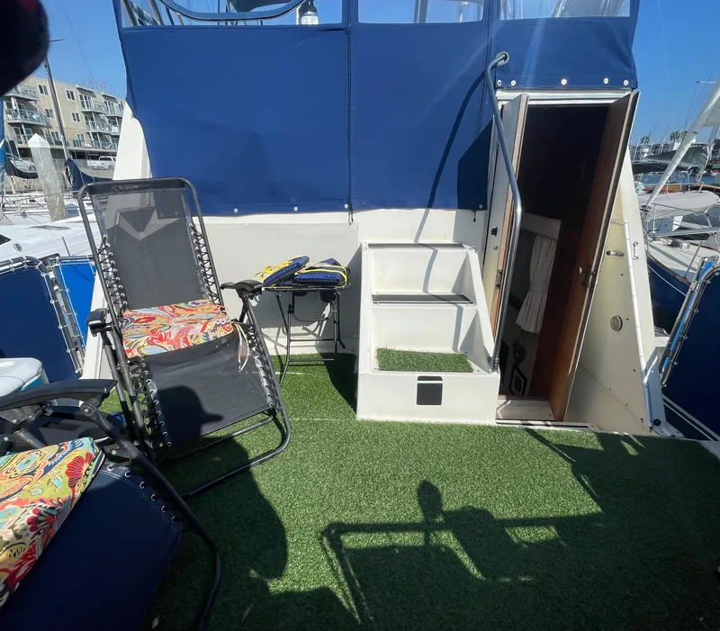 Slide: The Image of 1984 Uniflite Double Cabin Motor Yacht deck with chairs, artificial grass, and blue canopy. - 2