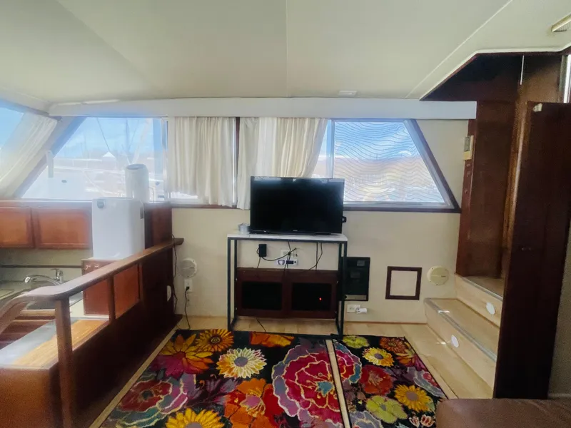 Slide: The Image of 1984 Uniflite Double Cabin Motor Yacht interior with TV, colorful rug, and wooden furnishings. - 22