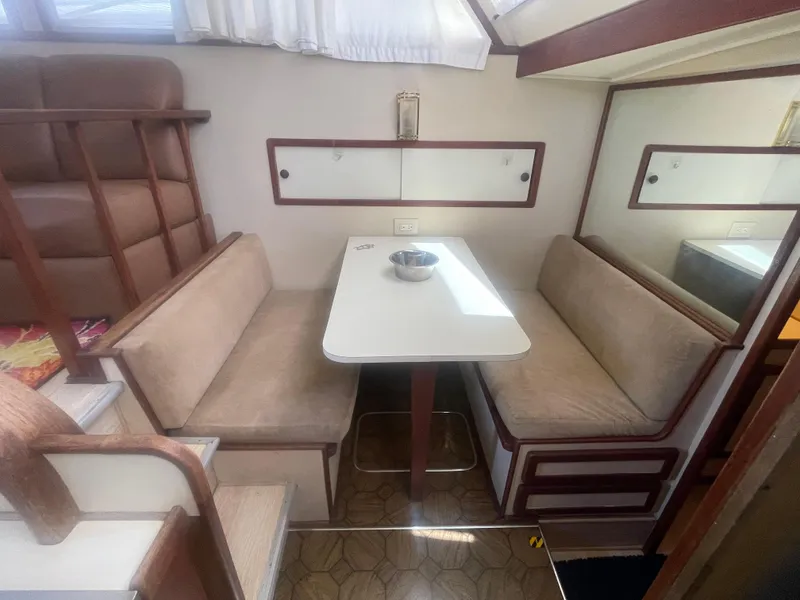 Slide: The Image of 1984 Uniflite Double Cabin Motor Yacht interior with dining area and cushioned seating. - 25