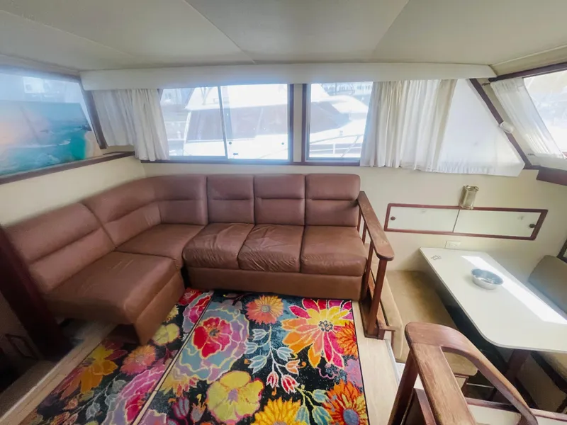 Slide: The Image of 1984 Uniflite Double Cabin Motor Yacht interior with brown sofa and colorful floral rug. - 26
