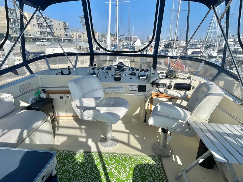 Slide: The Image of 1984 Uniflite Double Cabin Motor Yacht cockpit with white seating and marina view. - 3