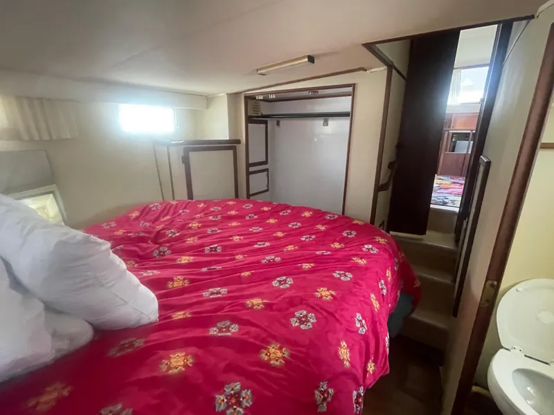 Slide: The Image of 1984 Uniflite Double Cabin Motor Yacht bedroom with red floral bedding and stairs. - 31