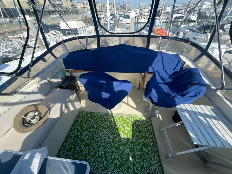 Slide: The Image of 1984 Uniflite Double Cabin Motor Yacht deck with blue covers and green patterned rug. - 4