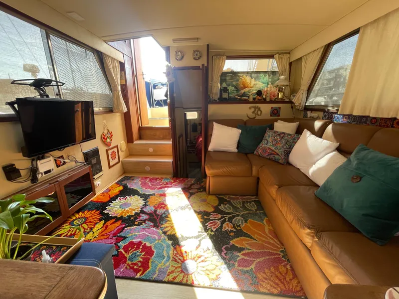 Slide: The Image of 1984 Uniflite Double Cabin Motor Yacht interior with cozy seating and vibrant floral rug. - 8