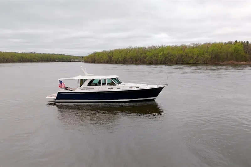 Slide: The Image of 2026 Sabre 45 Salon Express yacht cruising on a calm river with lush green shoreline. - 8