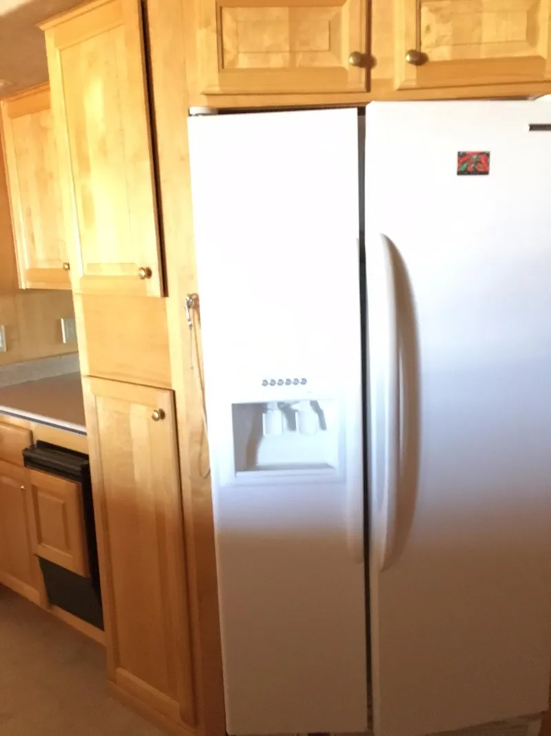 Slide: The Image of Wooden kitchen cabinets with a white refrigerator, featuring an ice dispenser. - 12