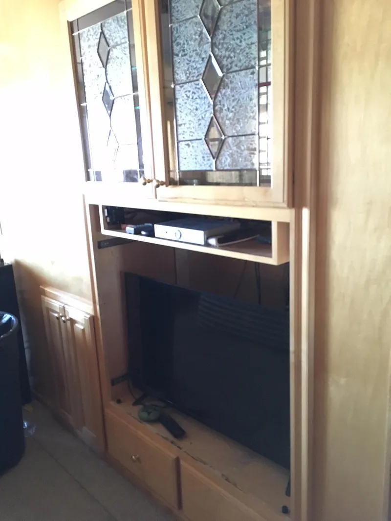 Slide: The Image of Wooden entertainment center with glass cabinet doors, housing a TV and electronic devices. - 16