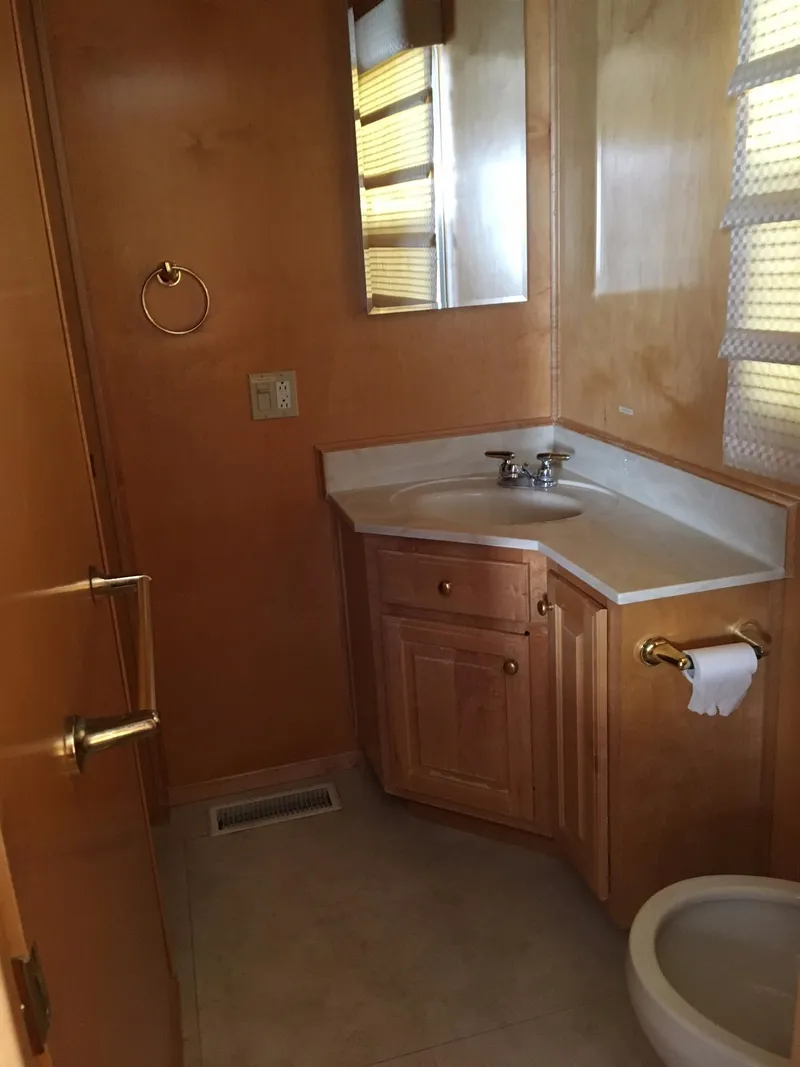 Slide: The Image of Compact wooden bathroom with corner sink, mirror, and toilet in a 2002 Sharpe model. - 5