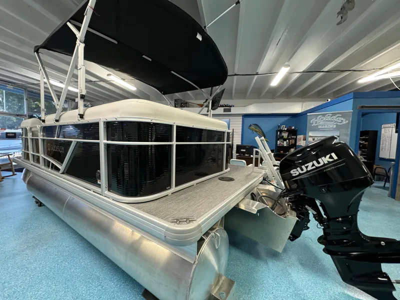 Slide: The Image of 2024 Sweetwater 1680 C pontoon boat with Suzuki outboard motor in showroom. - 2