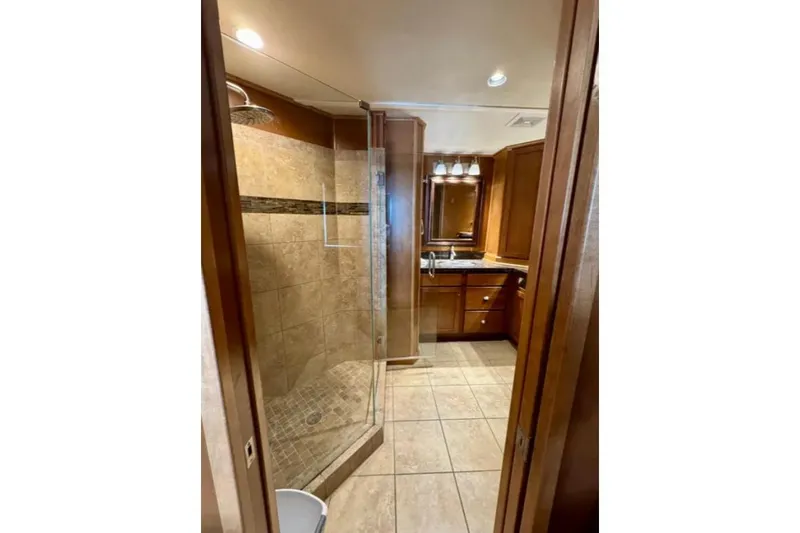 Slide: The Image of Luxurious bathroom in 2012 Bravada Helios Trip #7, featuring tiled shower and wooden cabinetry. - 5