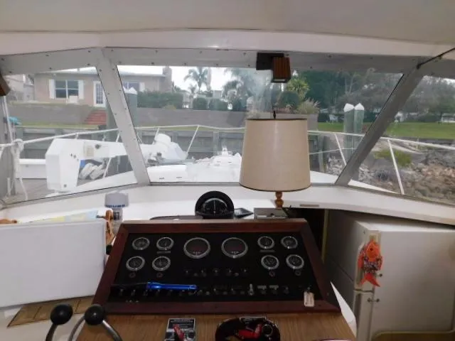 Slide: The Image of 1976 Bertram 42 Convertible yacht helm with gauges and lamp, docked in a marina. - 13