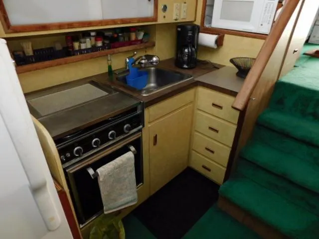 Slide: The Image of 1976 Bertram 42 Convertible kitchen with stove, sink, and microwave. - 17