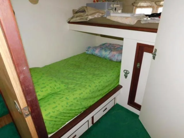 Slide: The Image of 1976 Bertram 42 Convertible cabin with green bedding and storage drawers. - 18