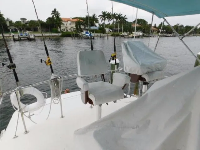 Slide: The Image of 1976 Bertram 42 Convertible boat deck with fishing chairs and rods, near waterfront homes. - 32