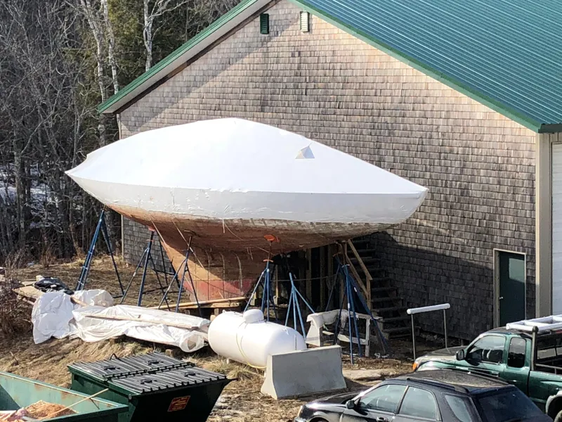 Slide: The Image of Historic 1903 Herreshoff Bar Harbor 31 sailboat under restoration near a wooden building. - 11