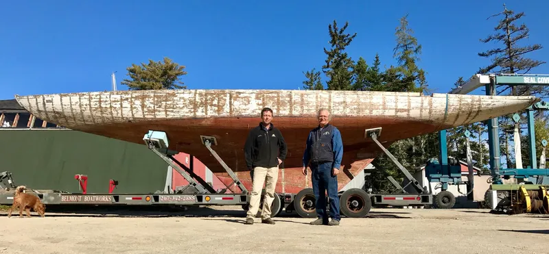 Slide: The Image of Two people stand beside a 1903 Herreshoff Bar Harbor 31 sailboat on a trailer. - 5