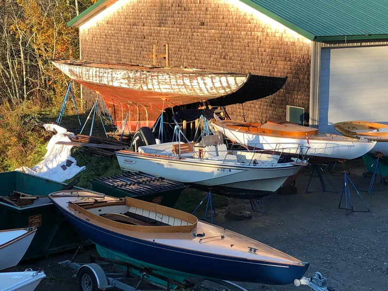 Slide: The Image of Historic 1903 Herreshoff Bar Harbor 31 sailboat in a boatyard with other vessels. - 7