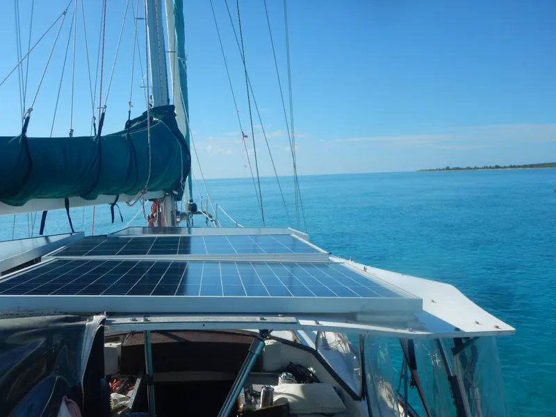 Slide: The Image of 1983 Whitby 42 sailboat with solar panels on deck, sailing in clear blue waters. - 10