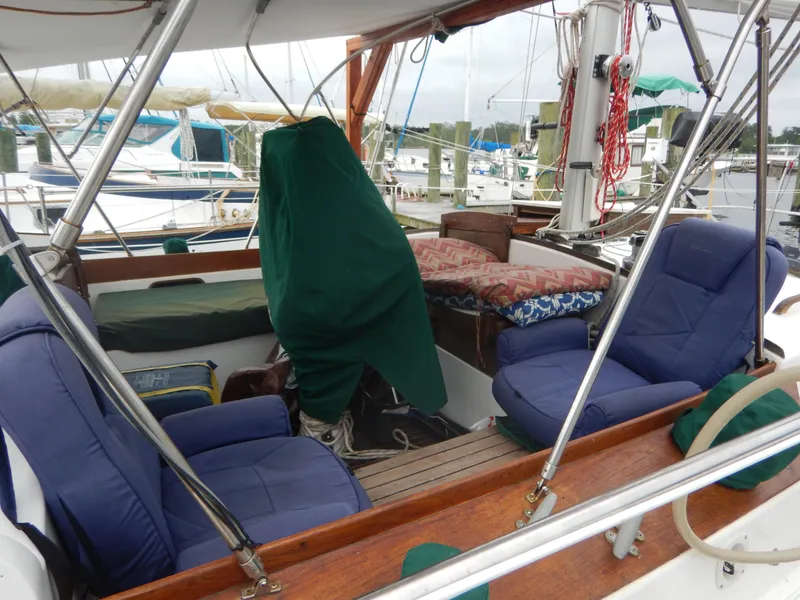 Slide: The Image of 1983 Whitby 42 sailboat cockpit with blue seats and marina background. - 12