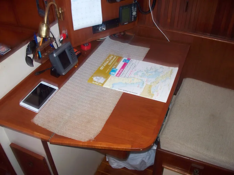 Slide: The Image of Navigation station on a 1983 Whitby 42 sailboat with chart and tablet. - 23