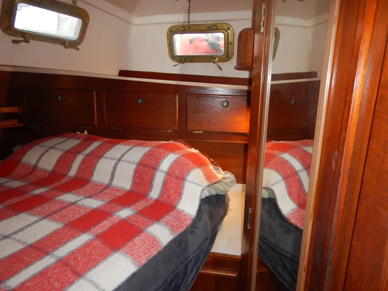 Slide: The Image of 1983 Whitby 42 sailboat cabin with bed and plaid blanket. - 24