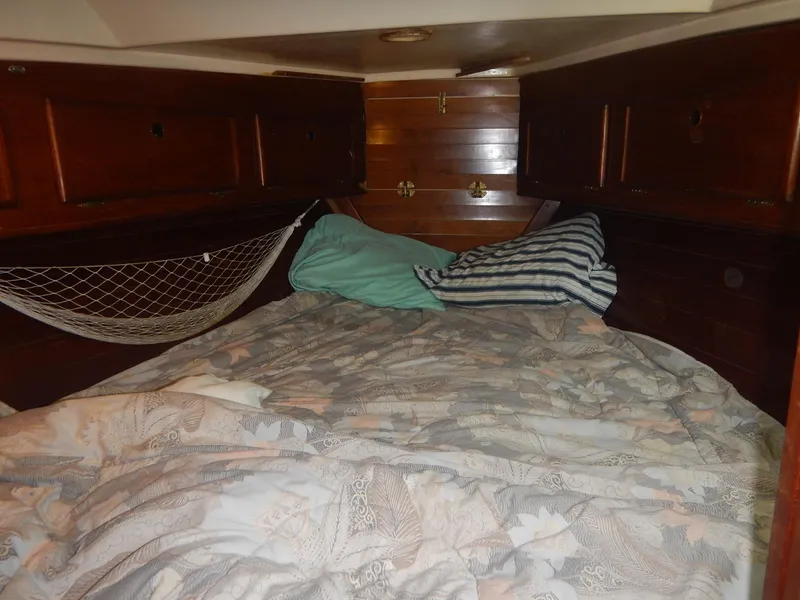 Slide: The Image of Cozy cabin bed in a 1983 Whitby 42 sailboat with wooden storage cabinets. - 26