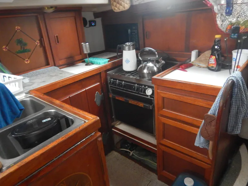 Slide: The Image of Compact kitchen area in a 1983 Whitby 42 sailboat with wooden cabinetry and stainless steel sink. - 27
