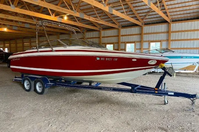 The Image of Red 2000 Cobalt 246 boat on trailer in a wooden storage facility. - 0