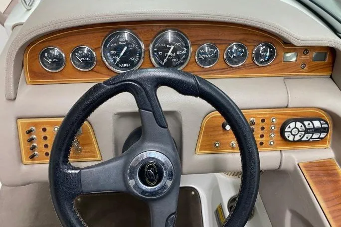 Slide: The Image of Steering wheel and dashboard of a 2000 Cobalt 246 boat with wood paneling and gauges. - 6