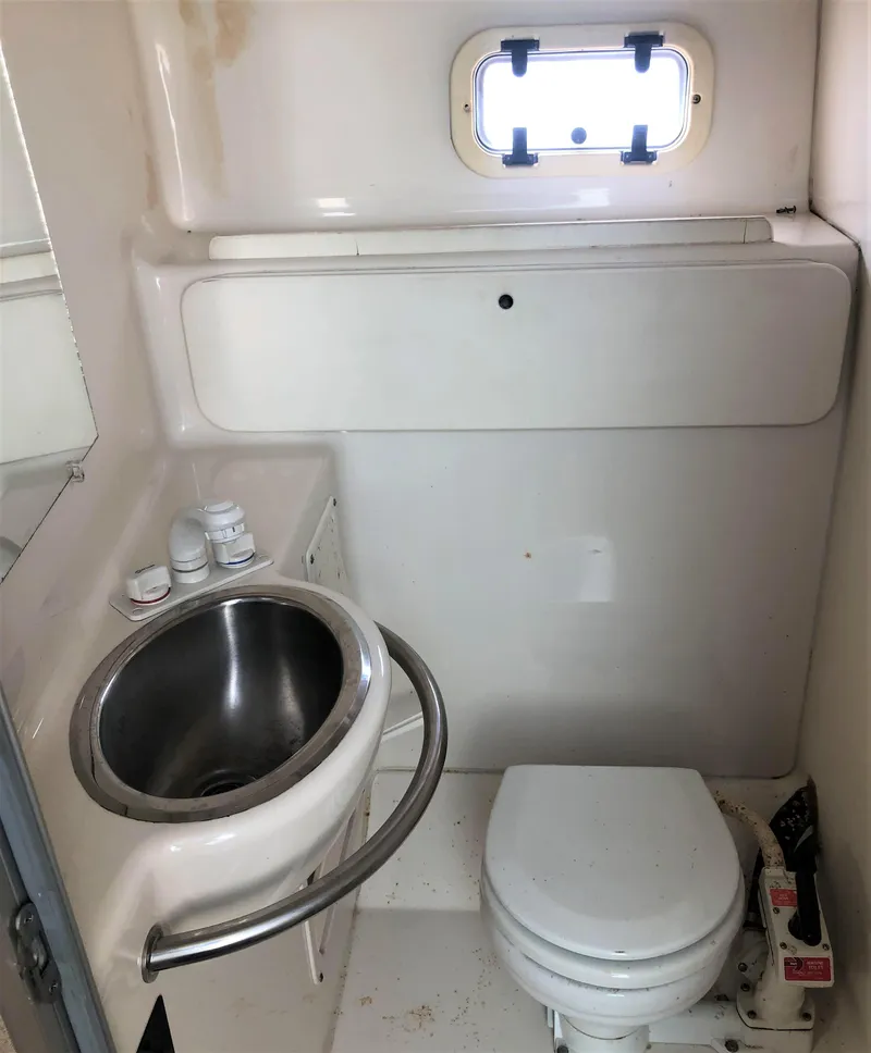 Slide: The Image of 1997 Maxum 3200 SCR boat bathroom with sink, toilet, and porthole window. - 13