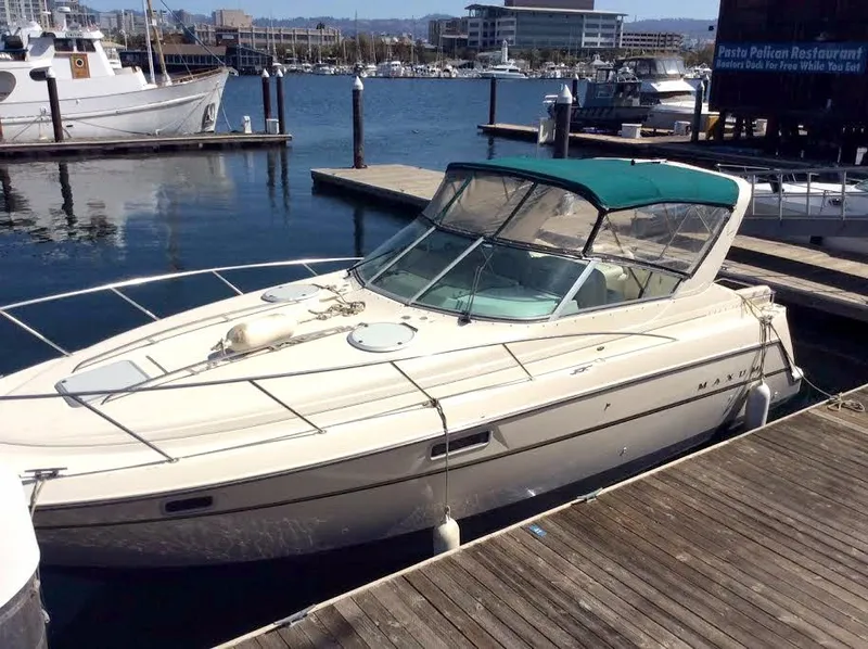 Slide: The Image of 1997 Maxum 3200 SCR boat docked at a marina with a green canopy. - 3