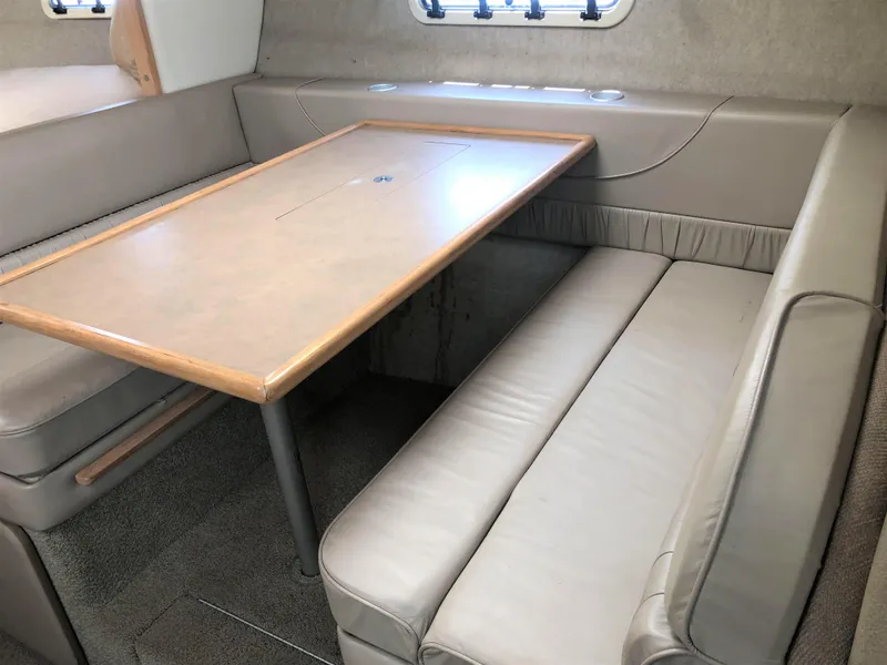Slide: The Image of Interior of 1997 Maxum 3200 SCR boat with beige seating and wooden table. - 9