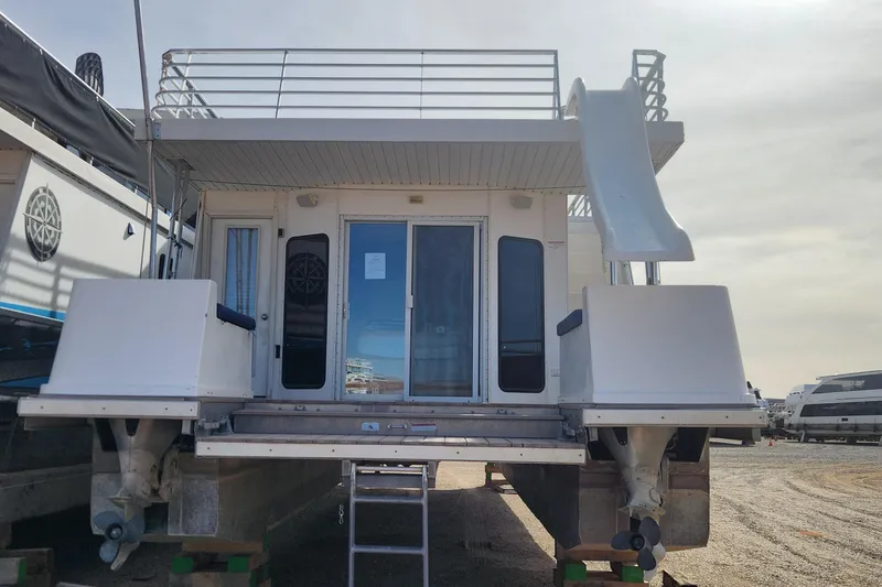 Slide: The Image of 2005 Sumerset Star Chaser houseboat with ropes and anchors, docked under a clear sky. - 3
