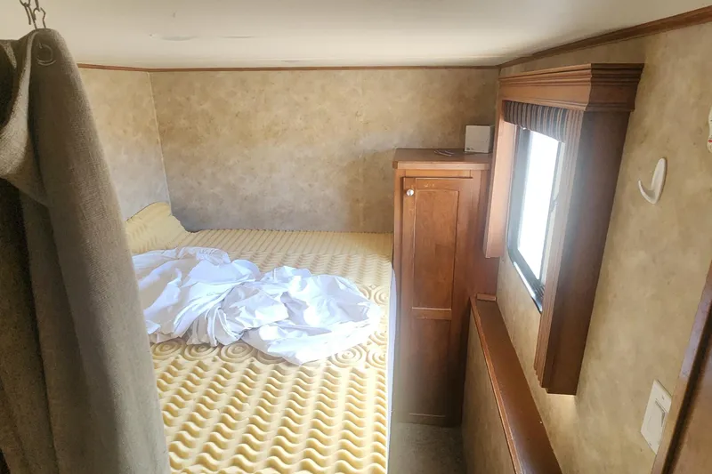 Slide: The Image of Interior of 2005 Sumerset Star Chaser, featuring a cozy bed and wooden cabinetry. - 9