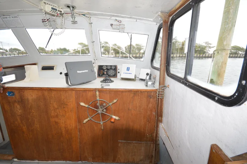 Slide: The Image of 1978 JC 31 boat interior with wooden helm, navigation equipment, and large windows overlooking water. - 12