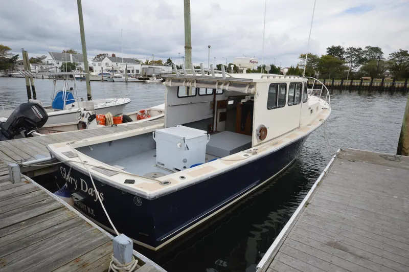 Slide: The Image of 1978 JC 31 boat docked at marina, featuring spacious deck and cabin. - 2