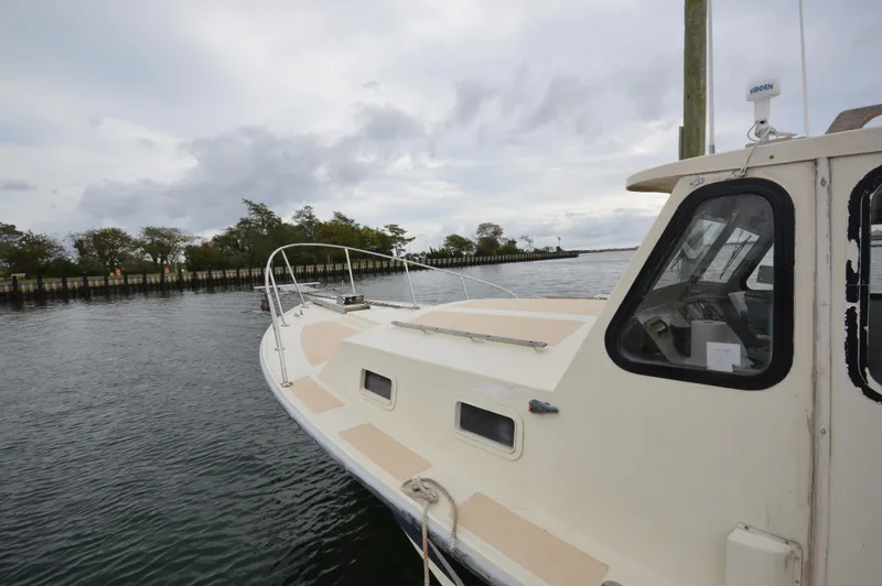 Slide: The Image of 1978 JC 31 boat docked by a calm waterfront under a cloudy sky. - 5