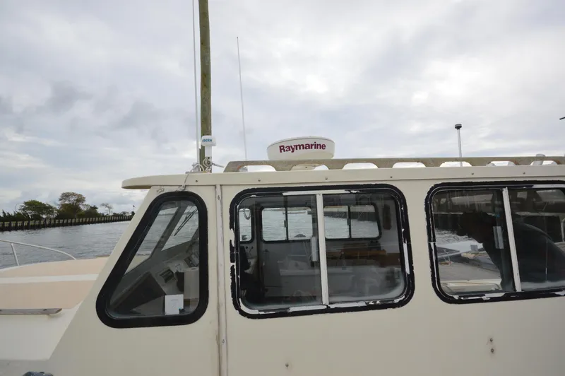 Slide: The Image of 1978 JC 31 boat with Raymarine equipment, docked by the water under cloudy skies. - 6