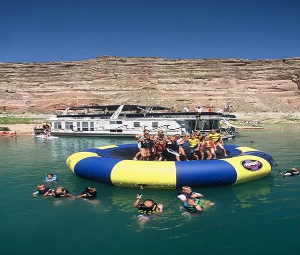 Slide: The Image of People enjoying a water trampoline near a houseboat on a lake, clear blue sky. - 6