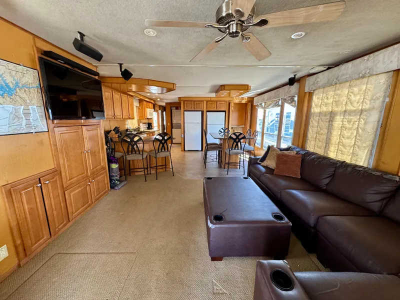 Slide: The Image of Spacious houseboat interior with leather seating, kitchen, and dining area, featuring wood cabinetry and ceiling fan. - 8