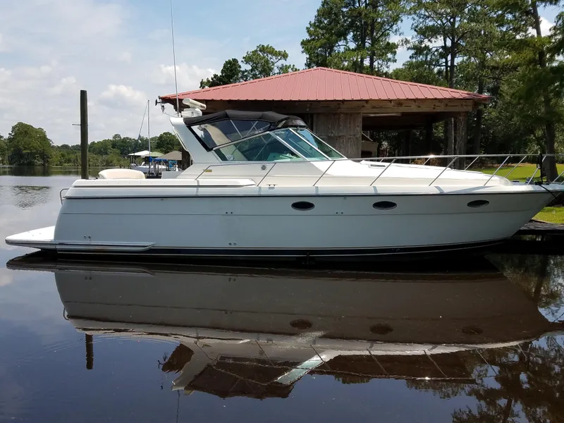 The Image of 1995 Tiara Yachts 3500 Express docked by a lakeside boathouse. - 0